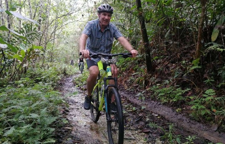 A man cycles down a muddy trail on his Kuching mountain biking adventure in Borneo