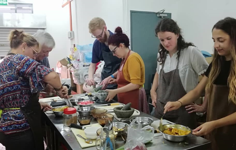 Guests work together, chopping, whisking, and tasting their creations in their cooking class Kuching.