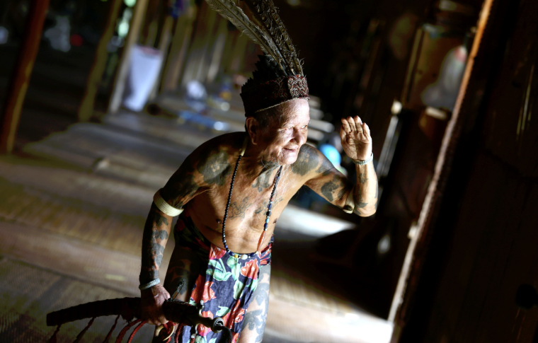 An elderly man in traditional dress looks out of his longhouse on this ultimate Borneo vacation.