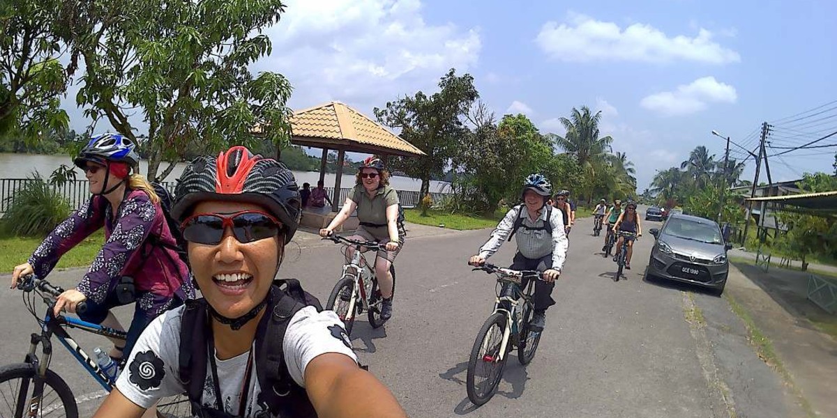 Farhah, the guide, leading some guests cycling through Malay villages along the bank of the Sarawak River.