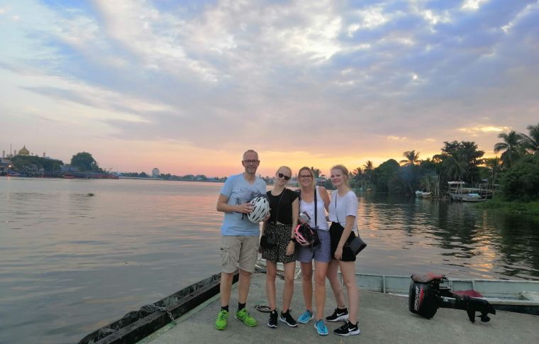 A family stand in front of the river as the sun sets on this Kuching tour.