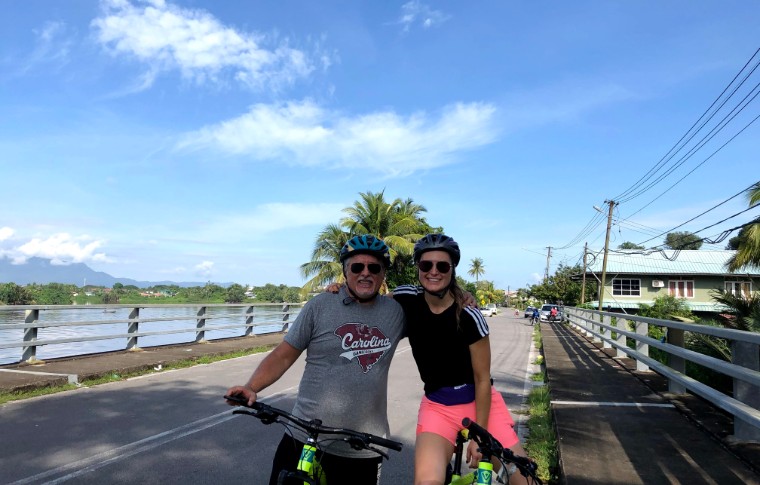 Two people on bicycles put their arms around each other for a photo.
