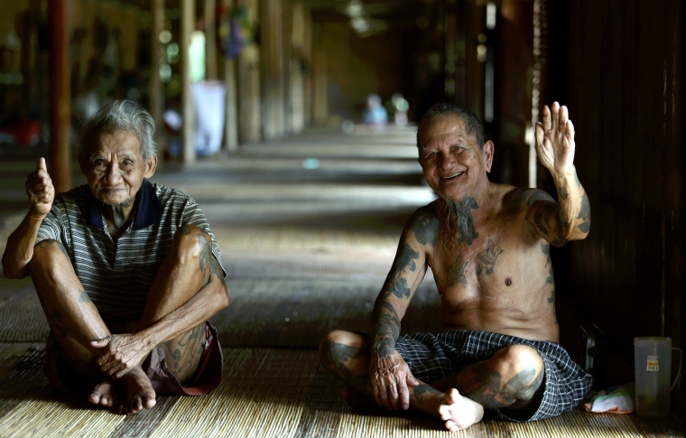 two Iban elders sitting on the floor of a longhouse