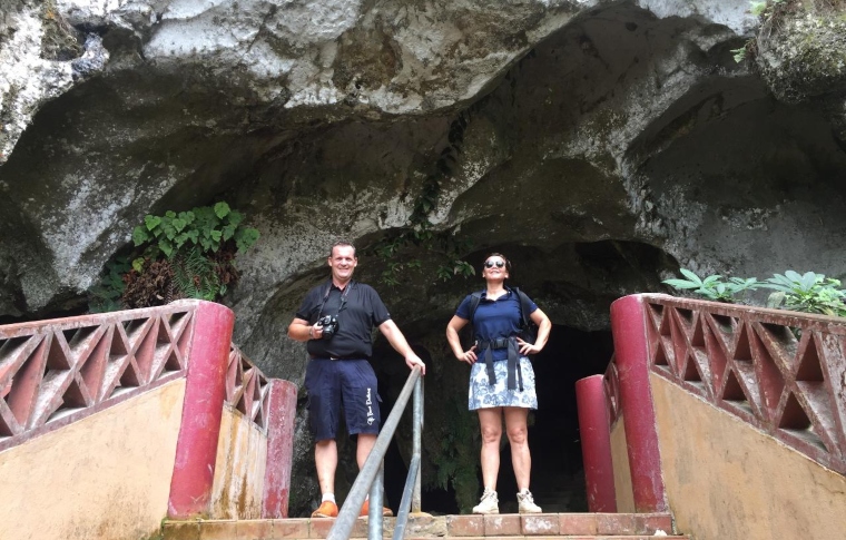 a couple of tourists standing at the entrance to a cave