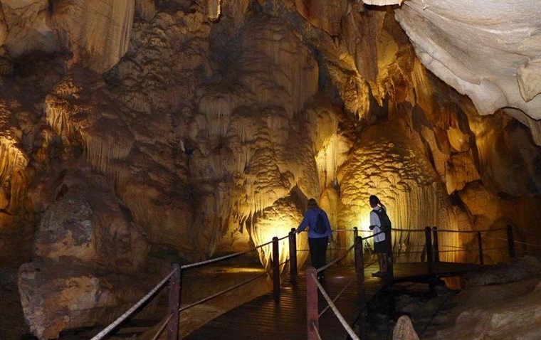 two tourists on the boardwalk in deep inside a cave